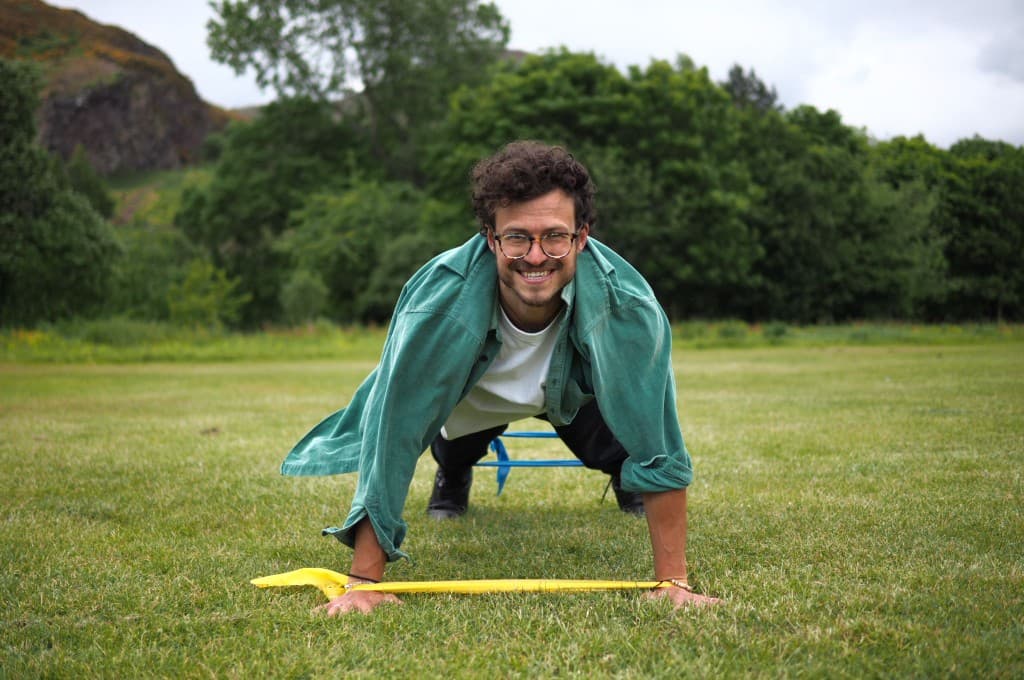 Anthony in a plank position outdoors with resistance bands